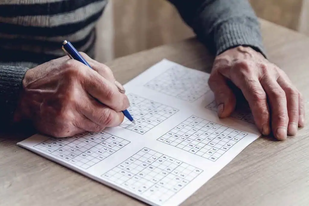 erfolgreich

Nahaufnahme der Hände einer älteren Person, die mit einem blauen Stift ein Sudoku-Rätsel auf einem Blatt Papier löst.